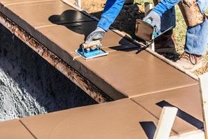 Construction Worker Using Hand Groover On Wet Cement Forming Coping Around New Pool photo