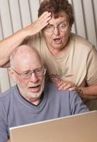 sonriente pareja de adultos mayores divirtiéndose en la computadora foto