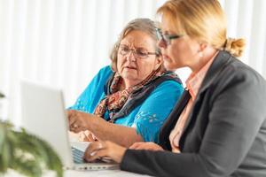 Woman Helping Senior Adult Lady on Laptop Computer photo