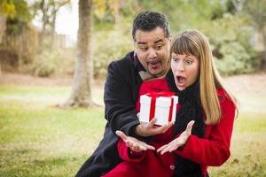 pareja de raza mixta compartiendo regalos de navidad o san valentín afuera foto