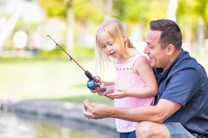 joven caucásico padre e hija divirtiéndose pescando en el lago foto