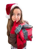 Thinking Girl Wearing A Christmas Santa Hat with Bow Wrapped Gift Isolated on White photo