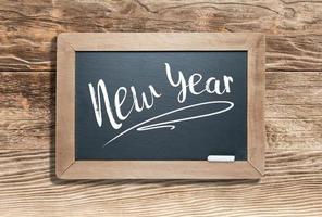 New Year Written on Slate Chalk Board Against Aged Wood Background photo