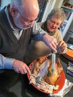 Senior Adult Couple Cutting the Holiday Turkey Together photo