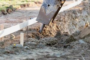Small Bulldozer Using A Breaker Attachment To Dig Hole photo
