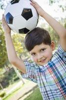 Lindo niño jugando con balón de fútbol en el parque foto