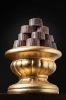 Stack of Fine Chocolates On Golden Pillar Dish With Dark Background photo