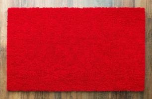 alfombra de bienvenida roja en blanco sobre fondo de piso de madera lista para su propio texto foto