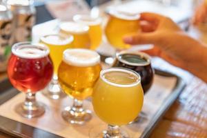 Female Hand Picking Up Glass of Micro Brew Beer From Variety on Tray photo