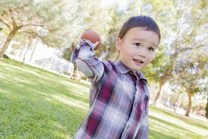 niño de raza mixta jugando al fútbol afuera foto