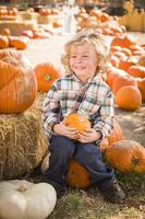 Little Boy Sitting and Holding His Pumpkin at Pumpkin Patch photo