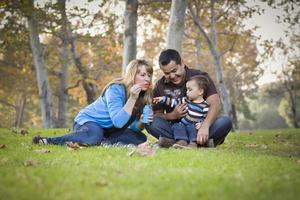 Happy Mixed Race Ethnic Family Playing with Bubbles In The Park photo