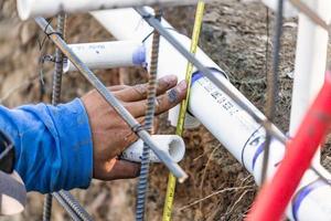 fontanero usando cinta métrica mientras instala tubería de pvc en el sitio de construcción foto