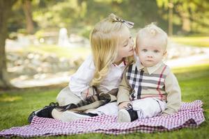 Sweet Little Girl Kisses Her Baby Brother at the Park photo