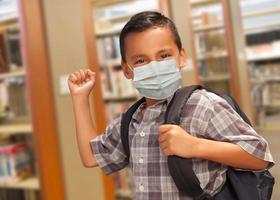 estudiante hispano con mascarilla con mochila en la biblioteca foto