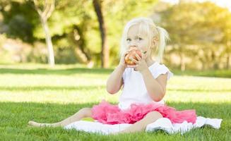 niña en la hierba comiendo manzana saludable foto