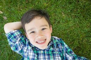 Mixed Race Chinese and Caucasian Young Boy Relaxing On His Back Outside On The Grass. photo