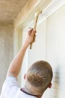 Professional Painter Cutting In With Brush to Paint Garage Door Frame photo