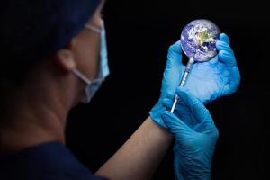 médico o enfermera administrando la vacuna a través de una jeringa en el planeta tierra foto