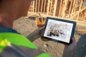 Female Construction Worker Reviewing Kitchen Illustration on Computer Pad at Construction Site photo