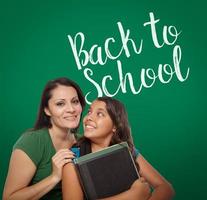 Back To School Written On Chalk Board Behind Proud Hispanic Mother and Daughter Student photo