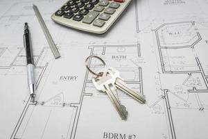 Pencil, Ruler, Calculator and Keys Resting on House Plans photo