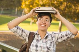 Mixed Race Female Student Holding Books on Her Head photo