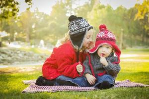 la niña susurra un secreto al hermanito al aire libre foto