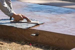 Construction Worker Applying Pressure to Texture Template On Wet Cement photo