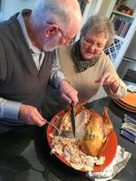 Senior Adult Couple Cutting the Holiday Turkey Together photo