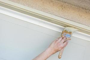 Professional Painter Cutting In With Brush to Paint Garage Door Frame photo