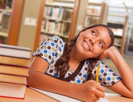 estudiante hispana soñando despierta mientras estudia en la biblioteca foto