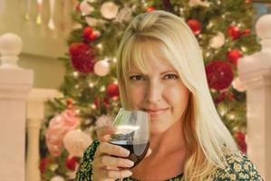 Blond Woman with Wine Glass In Front of Decrated Christmas Tree. photo