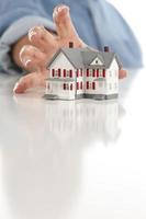 Womans Hand Reaching for Model House on White photo