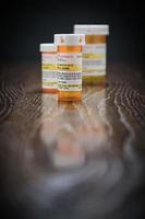 Variety of Non-Proprietary Prescription Medicine Bottles on Reflective Wooden Surface. photo