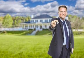 agente inmobiliario con llaves de casa frente a casa foto