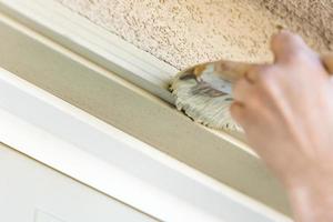 Professional Painter Cutting In With Brush to Paint Garage Door Frame photo