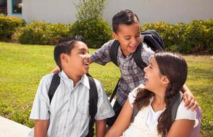 Young Hispanic Student Children Wearing Backpacks On School Campus photo