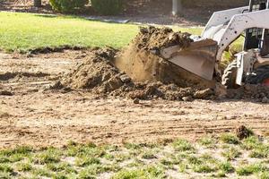 Small Bulldozer Digging In Yard For Pool Installation photo