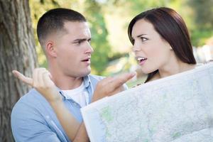 Lost and Confused Mixed Race Couple Looking Over Map Outside photo