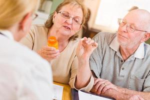 Doctor or Nurse Explaining Prescription Medicine to Senior Adult Couple photo