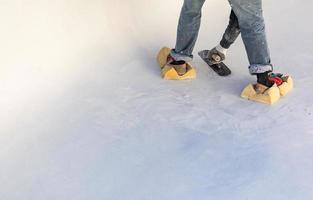 trabajador usando esponjas en los zapatos alisando el yeso húmedo de la piscina con una paleta foto