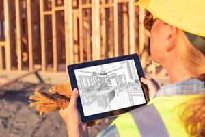 Female Construction Worker Reviewing Kitchen Drawing on Computer Pad at Construction Site photo