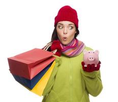 Concerned Mixed Race Woman Holding Shopping Bags and Piggybank photo