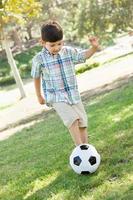Lindo niño jugando con balón de fútbol al aire libre en el parque. foto