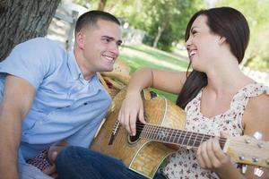 Mixed Race Couple at the Park Playing Guitar and Singing photo