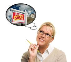 Woman with Thought Bubbles of a Sold Real Estate Sign photo