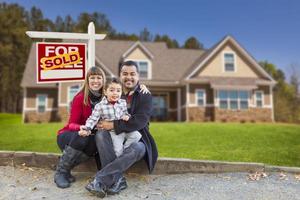 familia de raza mixta, hogar, vendido en venta signo de bienes raíces foto