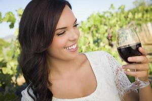 mujer adulta joven disfrutando de una copa de vino en un viñedo foto