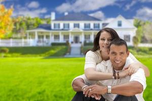 Happy Hispanic Young Couple in Front of Their New Home photo